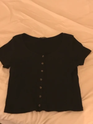 Monki tröja  - Svart tröja/crop top med bruna knappar på.