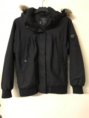 Vinter jacka  - Svart vinterjacka med avtagbar huva med pälskant. Den passar både tjejer och killar. Storlek 152, som en XXS