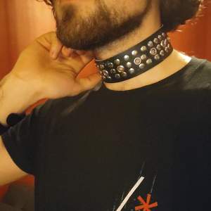 A thick choker/necklace, black leather with metal studs. 