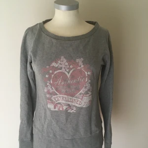 Grå tröja med tryck - En grå tröja med rosa tryck och bred urringning. Det är ett bra plag att göra en trift-flip med, till exempel croppa den eller liknande. 