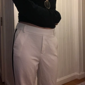 Vita kostymbyxor ZARA - Vita kostymbyxor med svarta ränder på sidorna. Byxorna kan ha skärp, har två fickor och kan bäras både lågmidjat och högmidjat. Byxorna är begagnade (lite noppriga men inte mycket. Byxorna är ca 86 cm långa och 75 cm breda i midjan, midjan har stretch.