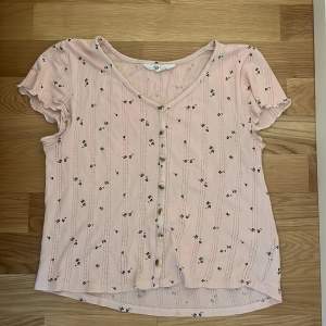 En rosa t-shirt med svarta blommor på från H&M  Storlek: 158/164