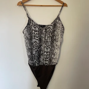 Body - Skitcool body med orminspirerat tryck!🤍🖤 Skit snygg till ett par jeans!! Storlek S (frakt ingår) 