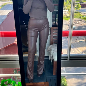 Bruna faux Leather byxor  - Faux leather byxor från Nelly. Använda 1 gång. Har klackar på bilden och är 1.60.