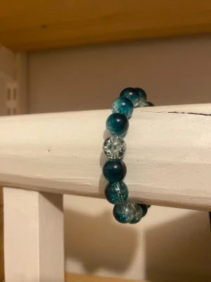 Grönt pärlarmband i glas 🦎 - Snyggt armband med runda pärlor i olika gröna matmor nyanser och transparent glas. Pärlorna har en cool, krackelerad effekt som ger extra stil. Undervik vatten🚿!!