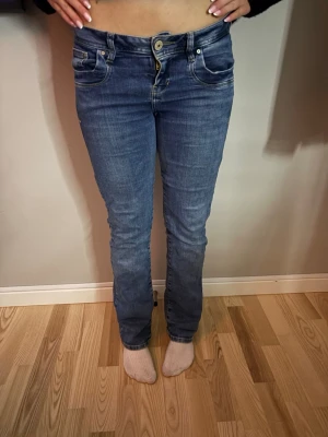 Blå ltb jeans med fickdetaljer - Snygga blå bootcut jeans från ltb med slitningar och coola fickdetaljer både fram och bak. Jeansen har låg midja, klassisk femficksdesign och kontrastsömmar. Perfekta för en avslappnad och trendig look.