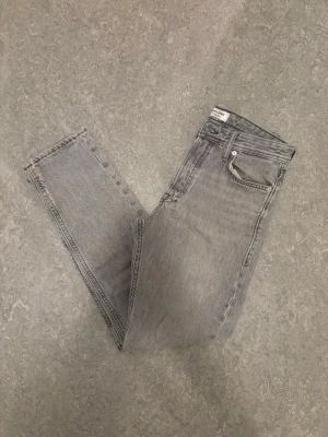 Grå jeans feån Jack & Jones Loose/chris - Snygga grå jeans från Jack & Jones med rak passform och klassisk femficksdesign. Jeansen heter loose/Chris och är i storleken 28/32