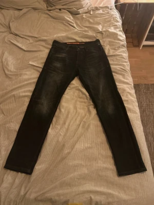 Mörkblåa tapered jeans Jack & Jones - Säljer ett par mörkblåa tapered fit jeans från Jack & Jones, modell Jeans Intelligence 1990.JJ.no. Jeansen har en snygg tvätt med slitningar och klassisk femficksdesign. Perfekta för dig som gillar en smalare passform och stilren look.