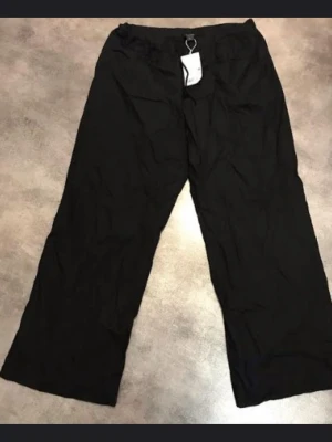 Monki avslappnande poplin byxor. Storlek XL - Svarta mjukisbyxor från Monki i storlek XL. Byxorna har en avslappnad, vid passform och resår i midjan för extra komfort. Perfekta för chill dagar eller när du vill ha en skön och loose stil. Materialet är mjukt och lätt, vilket gör dem extra bekväma.