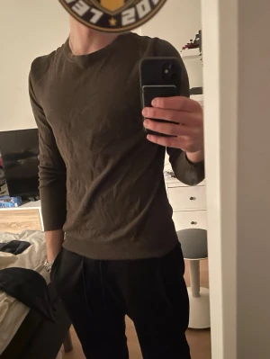 Brun långärmad tröja - En enkel och stilren mörkgrön långärmad tröja med rund halsringning. Tröjan har en smal passform och är tillverkad i ett mjukt, tunt material som passar perfekt till vardagslooken. Helt oandvänd. inga frågor.