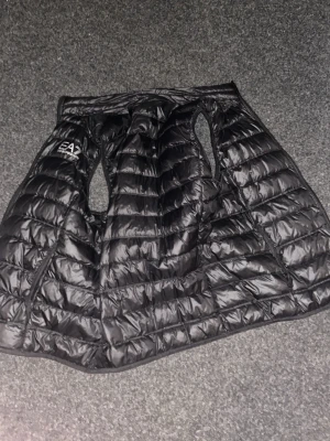 Ea7 väst  - Skön väst från ea7 med silvrig logga passar mig som brukar ha s/m i storlek fast den är xl säljs då jag har andra västar o jackor o denna inte kommer till användning använd fåtal gånger annars bara hängt i garderoben 