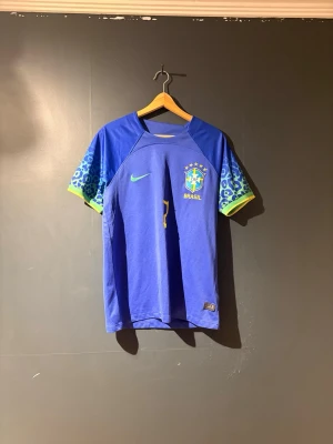 Blå Brasilien matchtröja Nike - Snygg blå Brasilien matchtröja från Nike med gul logga och emblem på bröstet. Tröjan är använd och har tappat lite av nummer 7 men även hela namnet ibak på tröjan i tvätten.
