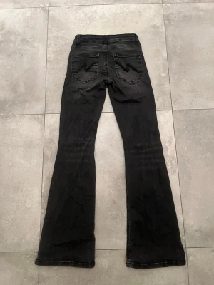 Svarta bootcut jeans från Nelly - Svarta bootcut jeans med hål vid knäna och detaljer på bakfickorna, från Nelly (Nypris 699kr)💕 Säljer byxorna för att dem inte används längre och blivit lite för korta. Dem köptes från Nellys hemsida och är i bra skick!!🩷 (Står ej för frakt)