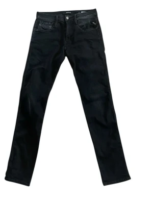 Svarta raka jeans från Replay - Snygga svarta jeans från Replay med klassisk femficksmodell och raka ben. Jeansen har diskreta sömmar och knappgylf. Materialet är denim med en mjuk känsla och stretch för extra komfort. Perfekta för dig som gillar en stilren och enkel look.
