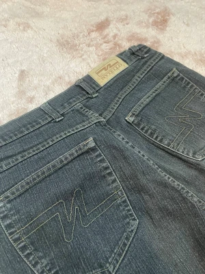 Svarta jeans från Nytello - Snygga svarta jeans,  Bakfickorna har ett coolt broderat mönster och jeansen har detaljer i mässing. Perfekta för dig som gillar en tidlös och avslappnad stil. Storlek 38, M passar även S om man har bred midja eller stor rumpa 