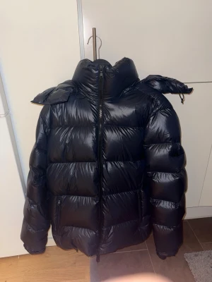 J. Lindeberg Creek Down Jacket Navy -Dunjacka - Storlek [M] - Säljer en J.Lindeberg Creek Down Jacket i färgen JL Navy. Köpte för 5500kr ny och haft endast två gånger, sen har den bara legat i garderoben. Fick en annan i present som jag har istället. Jackan är knappt använd. Helt i nyskick. Inga repor, inga skador. Allt är i nyskick.  En varm och stilren dunjacka med blank finish och huva — perfekt för höst och vinter. Perfekt för den som vill va varm men också ha stil. Skicka prisförslag, diskuterar gärna pris:) 