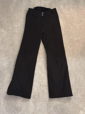 Svarta täckbyxor med vida ben från Colmar  - Säljer ett par svarta täckbyxor med två knappar i midjan och vida ben. 