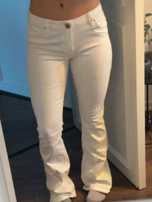 Vita utsvängda jeans - Snygga fräscha vita jeans med utsvängda ben (flared). Jeansen har låg midja och är tillverkade i ett stretchigt material som sitter tajt över låren och släpper ut vid vaden.