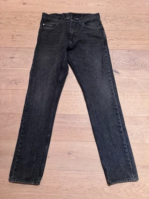 Svarta raka jeans Tiger of Sweden - Svarta raka jeans Tiger of Sweden med klassisk femficksmodell och raka ben. Jeansen har en diskret tvättad look och normal midja. Passar perfekt till en avslappnad stil och är tillverkade i ett mjukt denimtyg. Stl 29/32. Modell Pistolero. Nyskick!
