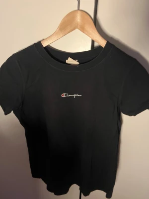 Svart Champion t-shirt med logga - Snygg svart t-shirt från Champion med liten broderad logga på bröstet. Perfekt som gåva till lillebrorsan osv, köpt på Urban outfiters för många år sen. Unisex storlek. 