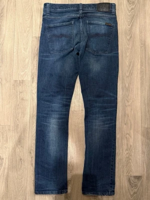 Nudie Grim Tim  - Sjukt snygga marinblåa Nudie Jeans Grim Tim ’True Dusk’ i fint skick i storlek W31/L32. Mått - Midja: 41cm, Benlängd: 103cm. Modellen är 185cm & 63kg. Hör av dig vid funderingar!🤝