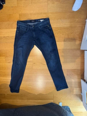 Mörkblå jeans Replay Anbass W34 L32 - Säljer ett par mörkblå jeans från Replay, modell Anbass. Jeansen har klassisk femficksdesign, smal passform och snygga slitningar. Tillverkade i stretchigt denimtyg för extra komfort. Perfekta för en trendig och avslappnad look. W34 L32