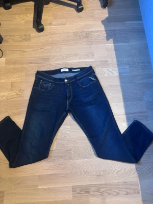 Mörkblå slim fit jeans från Replay anbass  W32 L30 - Snygga mörkblå jeans från Replay, modell Anbass med slim fit passform. Klassisk femficksdesign och bekvämt stretchigt jeanstyg. Perfekta för dig som gillar en smalare siluett och stilren look. W32-L30