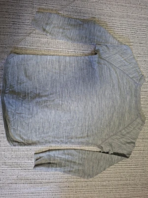 Ljusgrå långärmad tröja - Snygg ljusgrå långärmad topp från Merinowool i mjuk merinoull. Enkel och stilren design med rund halsringning och diskret logga nertill. Perfekt för lager-på-lager och passar året runt, eller för skidåkning 