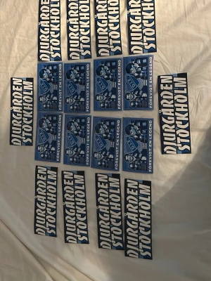 Djurgården Stockholm klistermärken - Ett gäng klistermärken med Djurgården Stockholm-tryck i svartvitt samt blåa märken med texten 'För evigt en legend' och bilder på spelare. Perfekt för dig som vill visa ditt stöd för Djurgården. Materialet är papper eller plast.