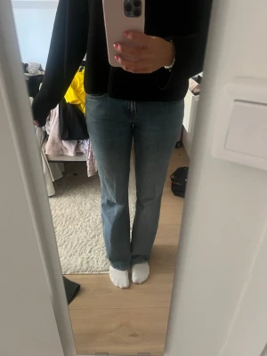 Blå bootcut jeans med klassisk passform - Säljer ett par blå bootcut jeans med klassisk passform och normal midja. Jeansen har en lätt tvättad look och raka ben som blir något utsvängda nertill. Perfekta för en avslappnad och trendig stil.