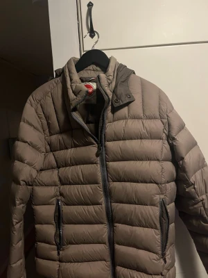 Brun pufferjacka från Colmar - Säljer en brun pufferjacka från Colmar med hög krage och två dragkedjeförsedda fickor framtill. Jackan har en quiltad design och Colmar-logga på bröstet. Perfekt för kalla dagar och riktigt snygg till streetwear-stilen. Inga defekter priset är inte hugget i sten