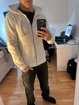 Vit hoodie med dragkedja från Newbie - Snygg vit hoodie från Newbie med dragkedja framtill, huva med dragsko och två fickor. Perfekt för lager-på-lager och enkel att matcha med andra plagg. Mjuk bomullskänsla och klassisk passform.