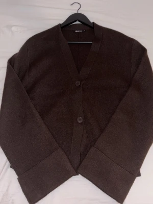Brun kofta med v-ringning från Gina Tricot  - Mysig brun kofta från Gina med två knappar framtill och djup v-ringning. Koftan har långa, vida ärmar med breda muddar och är gjord i ett mjukt stickat material. Säljer även denna i svart (samma modell). 