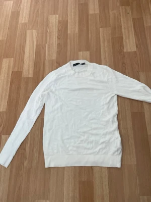 Vit stickad tröja  - Klassisk vit stickad tröja från 157 med rund halsringning och långa ärmar. Tröjan har ribbstickade muddar vid ärmslut och nederkant, vilket ger en snygg och enkel look. Perfekt att matcha med jeans eller kjol.