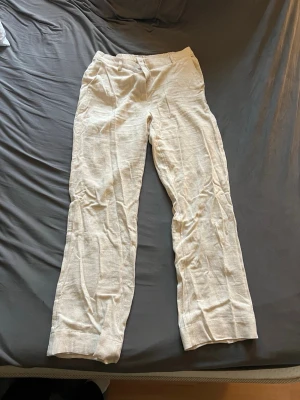 Beiga linnebyxor med raka ben från Nelly - Nya snygga beiga linnebyxor med raka ben och klassisk passform. Byxorna har resår baktill i midjan och stängs med knapp och dragkedja fram. Tillverkade i luftigt linnematerial. Byxorna är tyvärr för stora för mig så de är aldrig använda. 