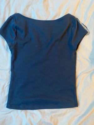 Mörkblå kortärmad topp - En enkel och stilren mörkblå topp med korta ärmar och rundad urringning. Toppen har en figurnära passform och är tillverkad i mjuk bomull, perfekt att matcha med jeans eller kjol.