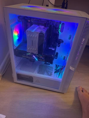 Vit stationär Gaming dator  - Säljer en vit stationär dator med genomskinlig sidopanel och RGB-belysning. Utrustad med ASUS GeForce RTX grafikkort och be quiet! CPU-kylare. Chassit har meshfront och flera RGB-fläktar för bra luftflöde. Perfekt för gaming och streaming.
