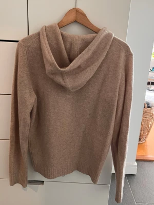 Beige hoodie i ull från Stenströms - Mysig beige hoodie från Stenströms i Yak/Ull. Tröjan har dragkedja framtill, huva och ribbade muddar. Perfekt för en avslappnad och stilren look. Passar dig som gillar klassiska och bekväma plagg. Storlek S men passar M