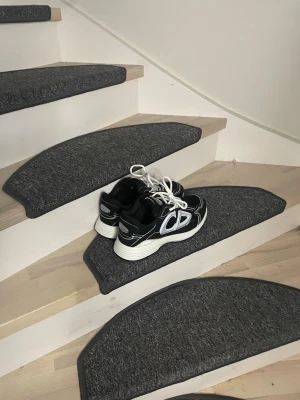 Svarta sneakers  - Snygga svarta sneakers med vita detaljer och tjock vit sula. Skorna har en sportig design med vita skosnören och tydliga loggor på sidorna. Perfekta för dig som gillar streetwear och vill ha en bekväm och trendig look.