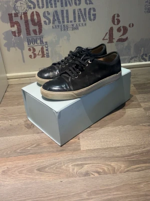 Lanvins  - Stilrena svarta sneakers i läder med vita sulor och svarta skosnören. Klassisk låg modell som passar till det mesta. Snygga metallhål för snörningen och diskret design utan synliga loggor. Perfekta för dig som gillar en clean och tidlös look.
