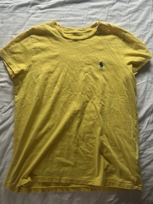 Polo Ralph Lauren Tshirt  - Gul Polo Ralph Lauren Tshirt i storlek S. Bra skick men har ett pyttelitet hål på framsidan men inget som man ser när man bär den och går nog lätt att sy utan att de syns. Skriv för frågor!