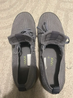 Grå Nike Air sneakers i stickad mesh - Snygga grå Nike Air sneakers med stickad mesh-överdel och klassiska snören. Skorna har en låg profil och genomskinlig sula som ger en modern vibe. Perfekta för dig som gillar stilrena och bekväma sneakers med sportig känsla.
