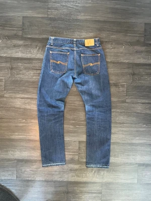 Nudie Jeans — Regular Ralf Dry Selvage - En av Nudies absolut fetaste modeller enligt mig och många andra i denim-communityt. Cotton-Barwool blend med tjockt selvedge ID — en äldre discontinued release som är svår att hitta.  Inte särskilt mycket använda — fades från tidigare ägare är i tidigt stadie med honeycombs och whiskers precis på gång. Perfekt för dig som vill starta ett nytt projekt på en riktigt fet modell och bygga upp dina egna fades från nästan noll.  Mått : Midja: 41 cm (82 cm runt) Längd: 106 cm Benöppning: 19 cm