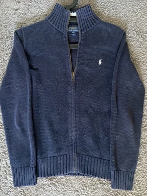 Mörkblå Ralph Lauren Tröja - En riktigt snygg navy Ralp Luren zip tröja. Bra skick, inga konstigheter. Dragkedjan har krånglat nån gång ibland men ingenting jag har märkt av på sistone. Tröjan är i storlek 14-16. Hör av dig direkt vid frågor eller funderingar!😄