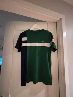 Lacoste t-shirt - En Lacoste t-shirt som du behöver för att uppgradera din garderob. Den är grön med feta mönster och har den klassiska Lacoste loggan på bröstet. Priset är ej hugget i sten 🪨 Skriv vid frågor!🤗