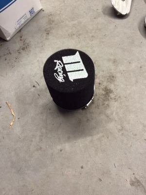 Svart luftfilter M Racing - Säljer ett svart runt luftfilter från M Racing med vit logga och text på ovansidan. Tillverkad i skumgummi och metallklämma för enkel montering. Perfekt för dig som vill uppgradera bilens luftintag.