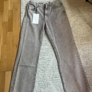 Jeanerica jeans Vega - Säljer ett par aldrig använda grå/beige jeans med raka ben och hög midja. Jeansen har klassisk femficksdesign och bälteshällor. Materialet är denim i bomull och färgen är en tvättad grå nyans som ger en cool vintagekänsla. Perfekta till sneakers eller boots. Nypris är 2800kr så fynda snabbt! Sista bilden visar jeansen på en modell och i bra ljus. 34/32