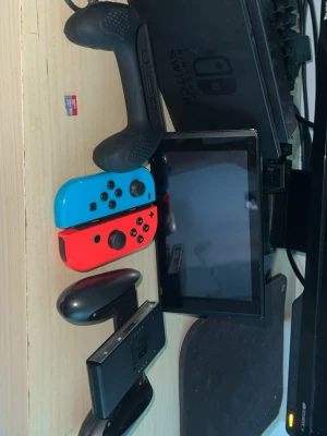 Nintendo Switch med tillbehör - Nintendo Switch med neonblå och neonröd Joy-Con, svart dockningsstation, svart Pro Controller och Joy-Con grip. Inkluderar även ett SanDisk Ultra 128GB microSD-kort för extra lagring. Perfekt för gaming hemma eller under resor. Om du har några frågar så svarar jag så snabbt så möjligt.