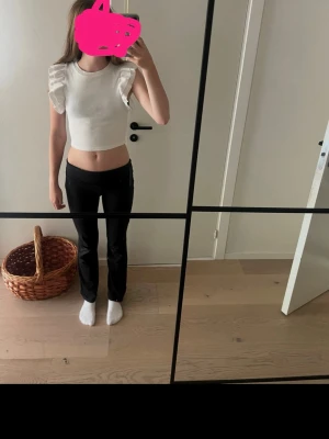 Vit topp med volangärmar - Supersöt vit topp med volangdetaljer på ärmarna. Ribbad struktur och rund halsringning. Perfekt för dig som vill ha en enkel men ändå trendig look. Passar till både jeans och kjol.