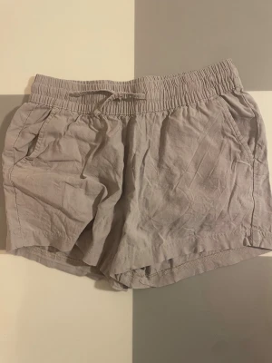 Beige shorts med snörning - Snygga beige shorts med elastisk midja och snörning framtill. Shortsen har två sidofickor och en bakficka, tillverkade i ett lätt och luftigt material som passar perfekt till varma dagar. De är i 150 men de är stretchiga så passar nog till en xxs😁Pris kan diskuteras🥰